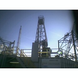 1981 Ford Bronco - A towering oil rig stands against the sky, a complex industrial structure.