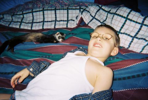 1990 Ford Bronco - A child and a ferret relax on a bed covered in patterned blankets.
