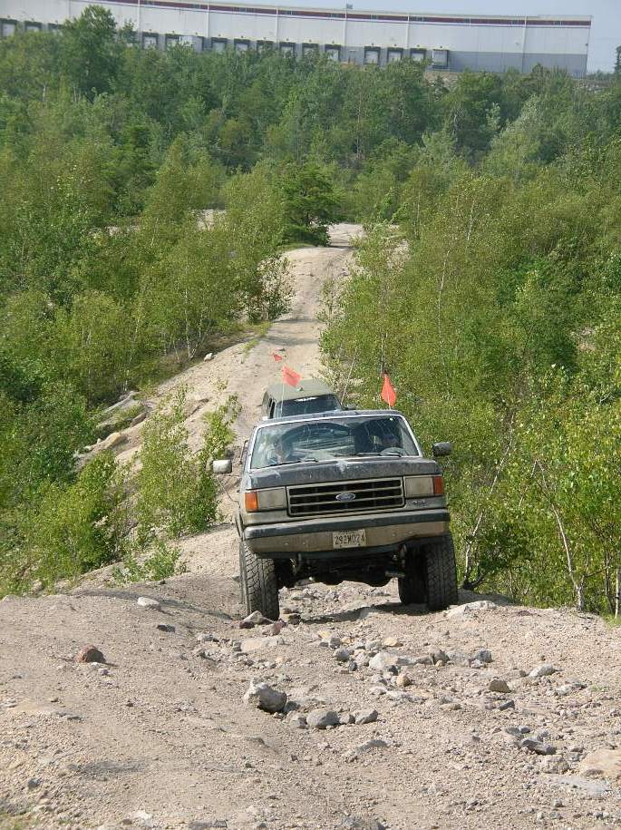 Ford F-Series truck climbing a dirt hill, another vehicle behind it