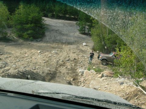 1995 Ford Bronco - A brown 1992 Ford Bronco is parked on a dirt road, with a person standing nearby, surrounded by trees and rocky terrain.