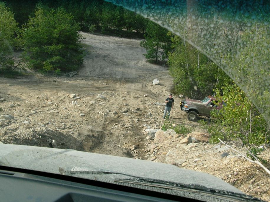 Brown 1992 Ford Bronco parked on a dirt road with a person standing next to it
