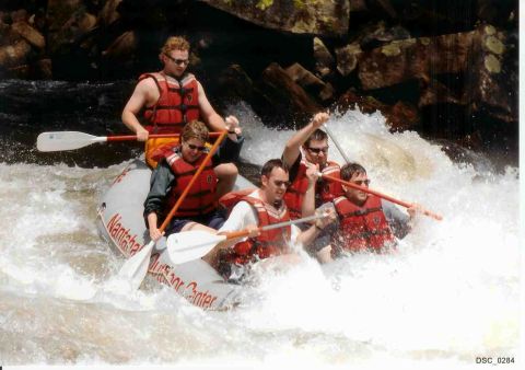 1985 Ford LTD Crown Victoria - A group of people navigate a rapid in a raft, paddling through whitewater.