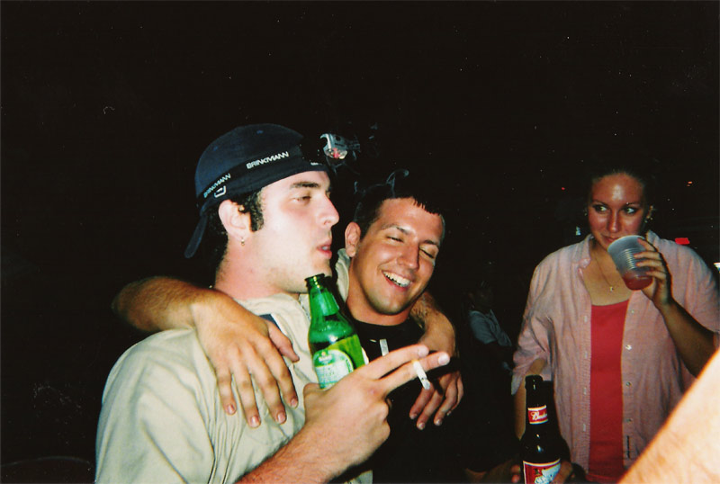 Three people at a party, two men holding drinks and a woman holding a cup