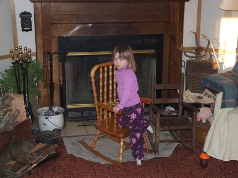 1966 Ford Ranchero - A young child sits in a wooden rocking chair, posing in front of a fireplace with decorative items around.