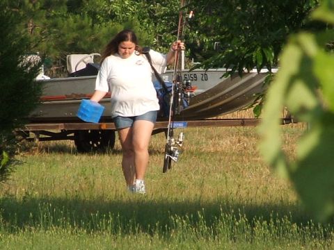 1966 Ford Ranchero - Woman carrying fishing gear walks past a boat on a trailer.