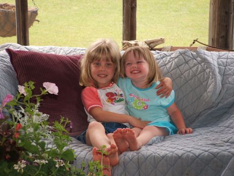 1966 Ford Ranchero - Two happy young girls share a hug while sitting on a couch outdoors.