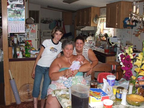 1966 Ford Ranchero - A family gathers in a kitchen, with a baby being held by a woman, while another woman and a girl stand nearby.
