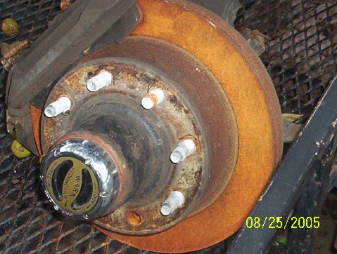 1989 Ford Bronco - Close-up of a heavily rusted brake rotor and hub assembly with a WARN locking mechanism.