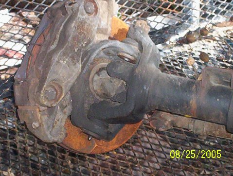 1989 Ford Bronco - A close-up view of a vehicle's front axle assembly, including the brake caliper and rotor, is shown.