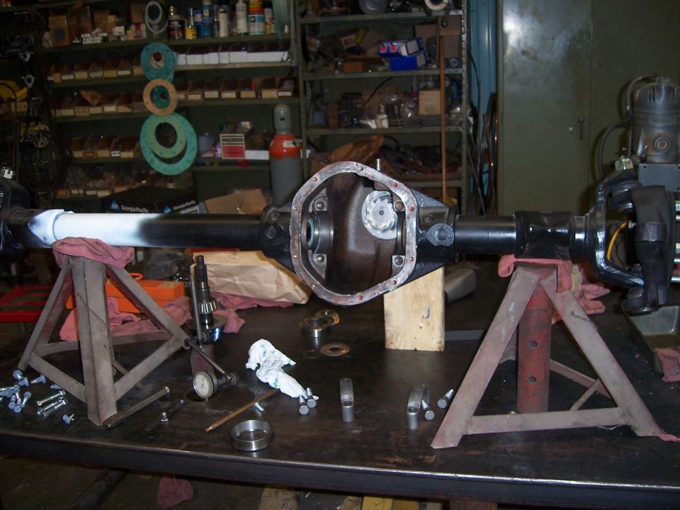 Differential axle assembly on jack stands, disassembled with tools and parts on workbench