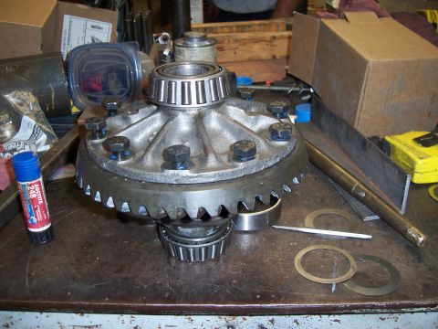 1983 Ford Bronco - A differential gear assembly with bearings and a ring gear is shown on a workbench with various tools and parts.