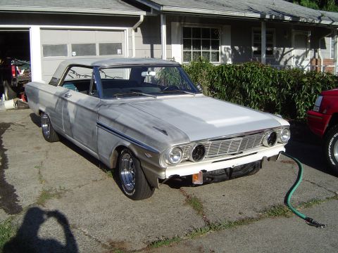 1964 Ford Fairlane - A primer-painted 1962 Ford Falcon convertible sits in a driveway, ready for its next stage of restoration.