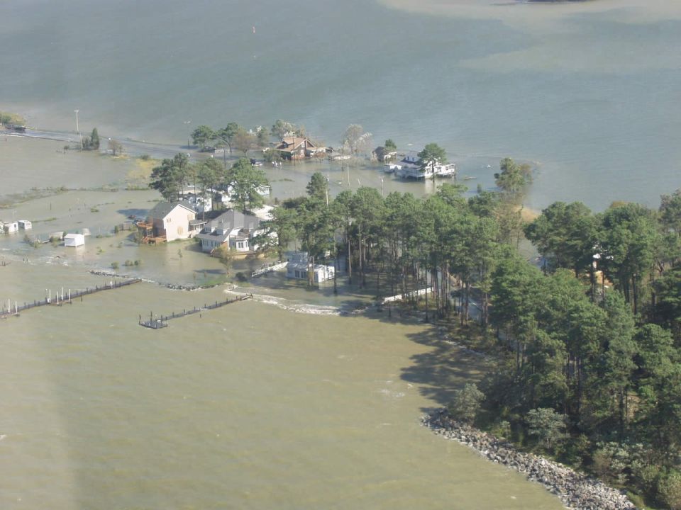 Flooded coastal scene with houses submerged in water and trees
