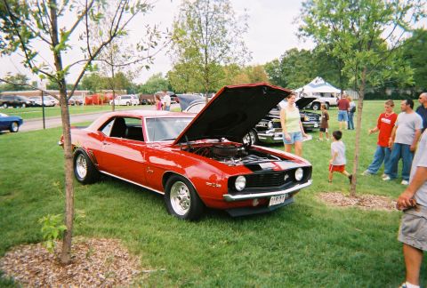 1996 Ford F-150 - A red 1969 Chevrolet Camaro is displayed with its hood up at an outdoor car show.