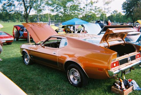 1996 Ford F-150 - Orange 1971 Ford Mustang at a car show, with hoods and trunk open, surrounded by other vehicles.