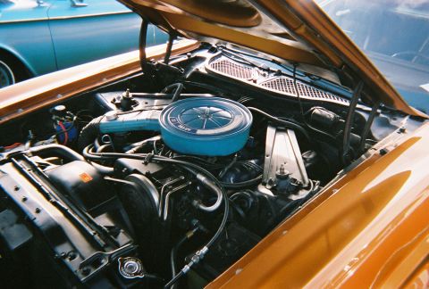 1996 Ford F-150 - The engine bay of a vintage orange car is shown, with a blue air cleaner assembly and other engine components visible.