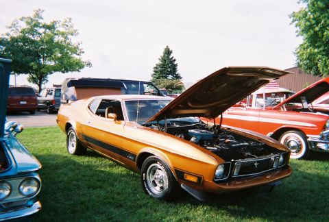 1996 Ford F-150 - A classic orange 1971 Ford Mustang coupe is displayed with its hood open at a car show.