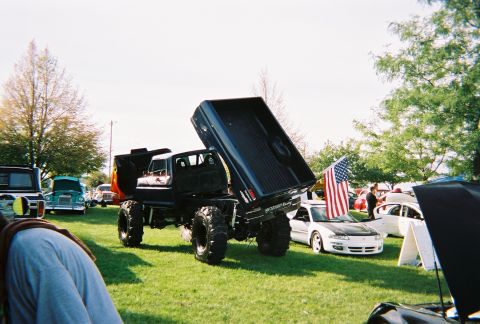 1996 Ford F-150 - Modified dump truck at a car show with other vehicles and an American flag.