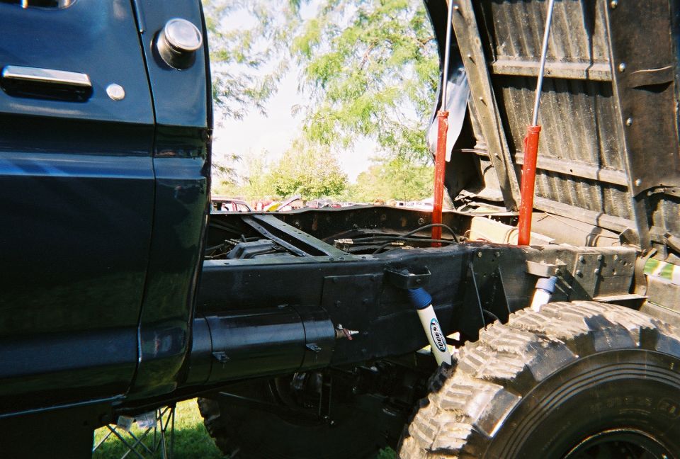 Side view of dark blue truck chassis with dump bed hydraulics and large tires
