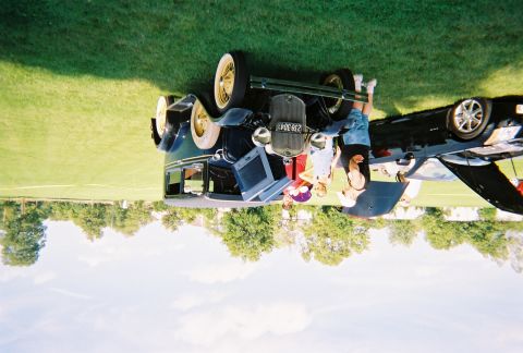 1996 Ford F-150 - A group of people stand around a classic dark blue automobile, with a modern car nearby.