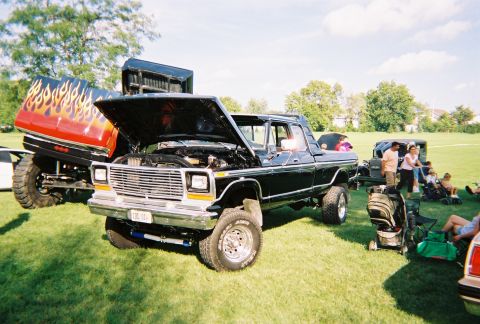 1996 Ford F-150 - A black pickup truck is displayed with its hood open at an outdoor event, with other vehicles and spectators present.
