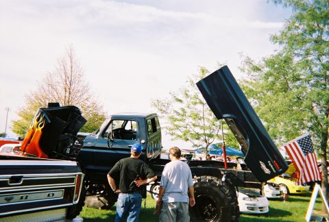 1996 Ford F-150 - Two men observe a modified Ford truck with its hood and bed open at an outdoor event.