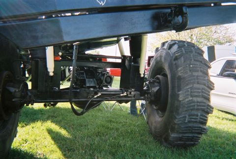 1996 Ford F-150 - Close-up view of the undercarriage and suspension system of a modified truck, with another vehicle visible in the background.