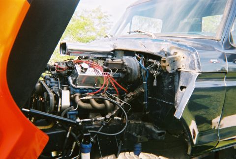 1996 Ford F-150 - Close-up of a modified truck engine with the hood open, revealing custom parts.