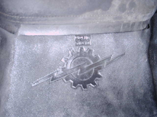 Embroidered gear-and-lightning-bolt patch on a faded cloth jacket or shirt