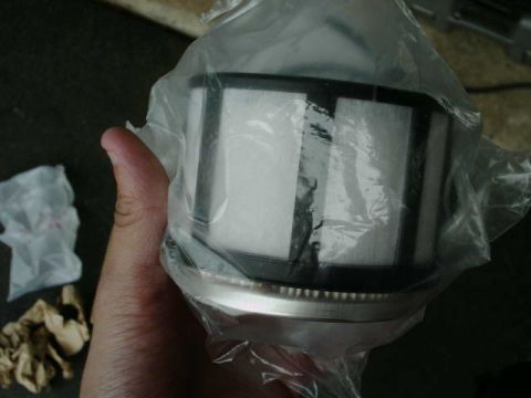 2002 Ford F-250 - New oil filter in plastic packaging, held by a hand. Supermotors.net logo visible.