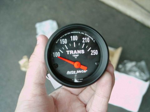 2002 Ford F-250 - An Auto Meter transmission temperature gauge is held in a hand, showing a reading of 100 degrees Fahrenheit.