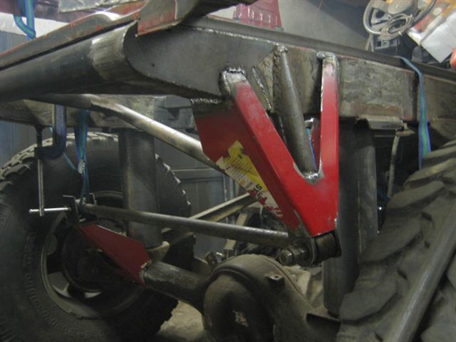 Modified vehicle chassis with red suspension components and large tire. Visible text: SUPERMOTORS