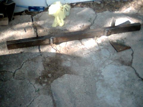 1992 Ford Bronco - A metal bar with brackets is visible on cracked concrete, with a yellow plastic bag in the background.
