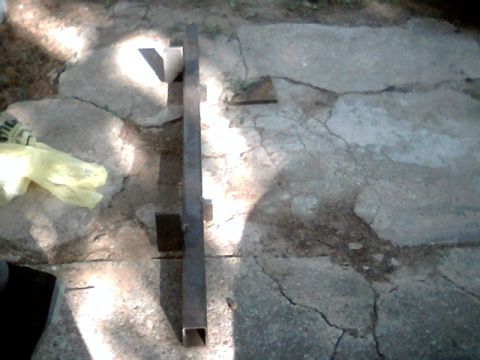 1992 Ford Bronco - A metal bracket is shown resting on a cracked concrete surface, with a yellow plastic bag visible to the left.