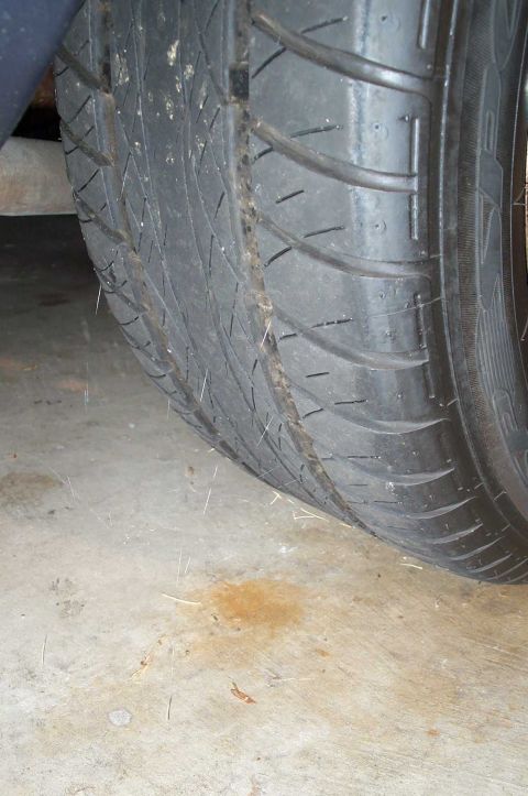 1998 Ford Crown Victoria - The tire tread is significantly worn, and there's a small stain on the concrete below.