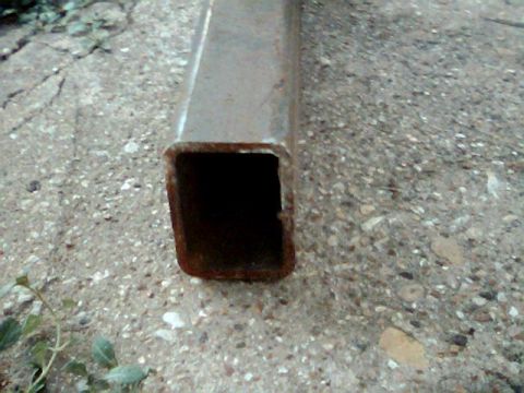 1992 Ford Bronco - A close-up view of a rusty metal tube on a concrete and gravel ground.