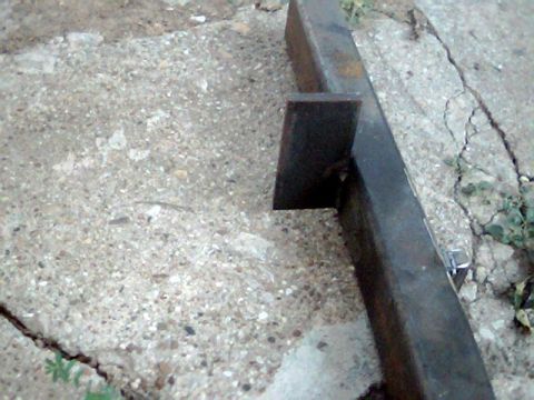 1992 Ford Bronco - Metal bracket attached to a steel tube on a concrete surface.
