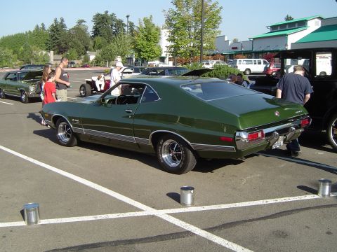 1964 Ford Fairlane - A green coupe with distinctive chrome trim is parked at an outdoor event.