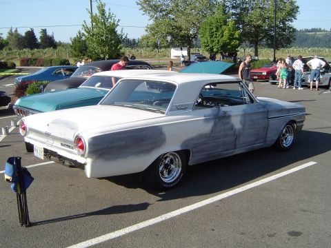 1964 Ford Fairlane - A white 1964 Ford Fairlane coupe is parked in a lot, showing primer patches on its bodywork.