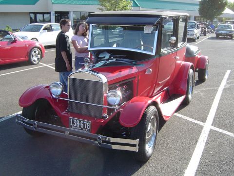 1964 Ford Fairlane - A red vintage car from 1927 is parked in a lot with other vehicles.