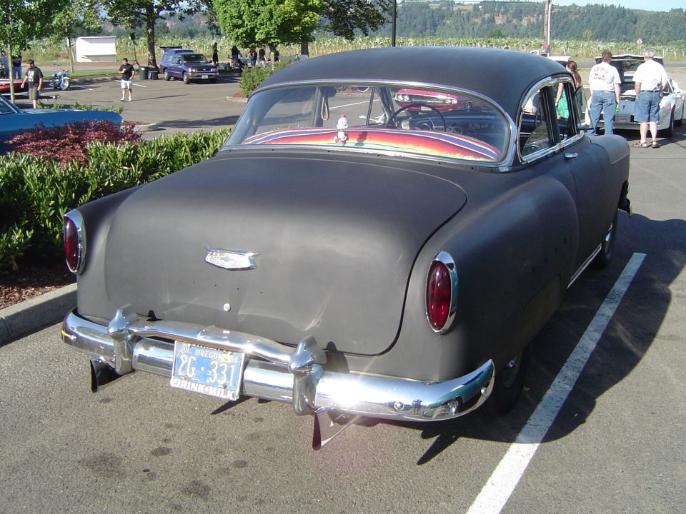 Matte black sedan parked in a lot, rear view. License plate reads 2G-331