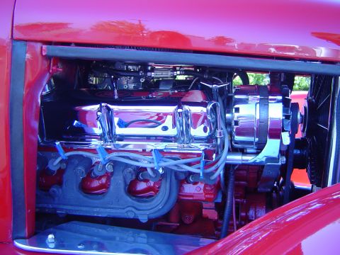 1964 Ford Fairlane - Close-up view of a red engine bay with polished chrome components and visible wiring.