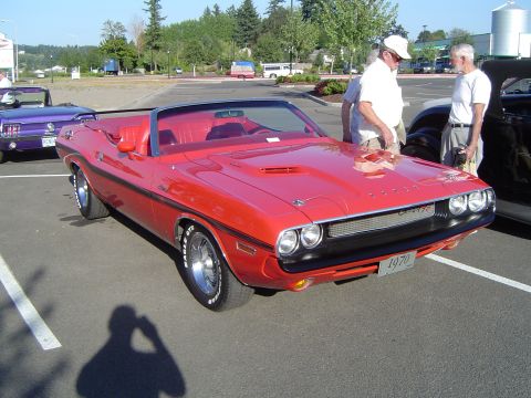 1964 Ford Fairlane - A red 1970 Dodge Challenger convertible is parked in a lot, with two men standing nearby and another purple convertible in the background.