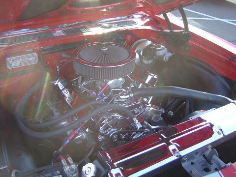 1964 Ford Fairlane - The engine bay of a red car is shown with a large air filter and chrome components.