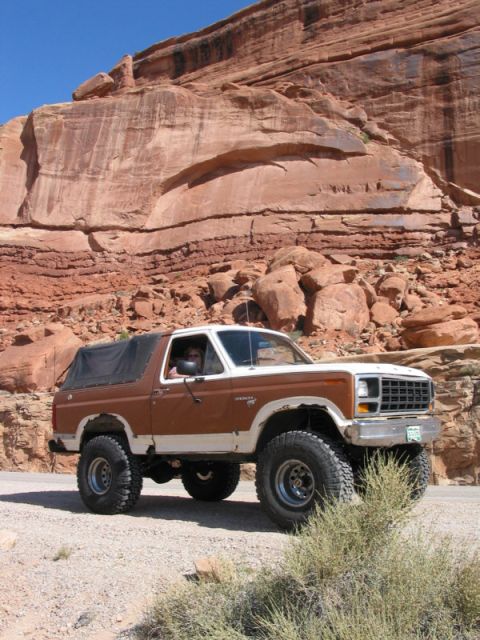 1981 Ford Bronco - This lifted Ford Bronco is parked in a desert landscape with large red rock formations in the background.
