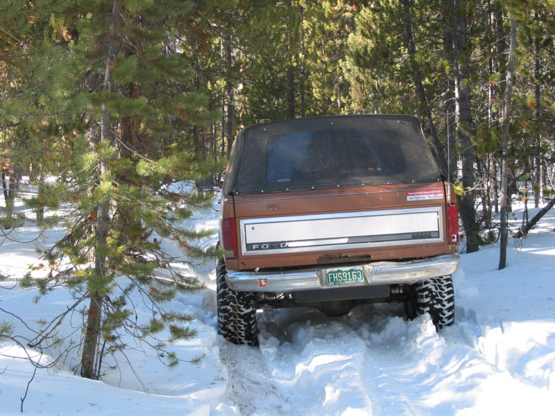 1981 Ford Bronco rear view driving in snow covered forest road