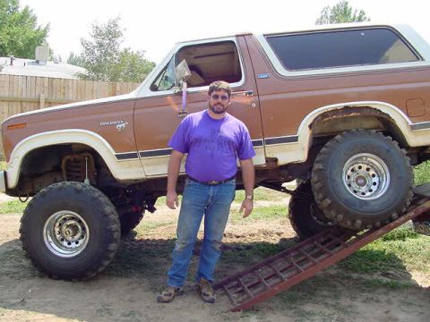 1981 Ford Bronco - Man stands next to a heavily modified 1981 Ford Bronco with oversized tires.