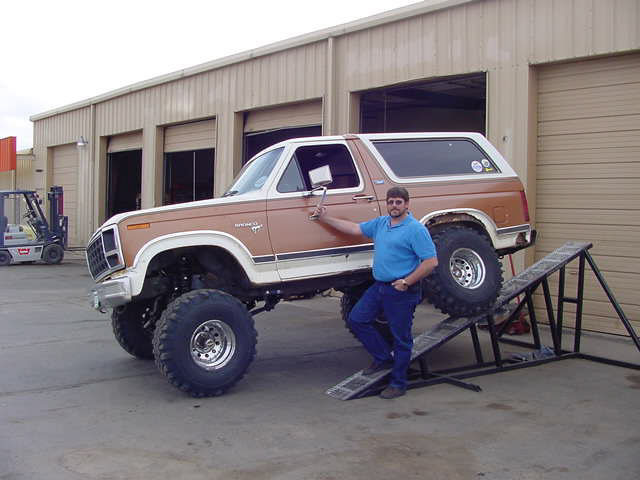 Man standing next to a lifted Ford Bronco on ramps