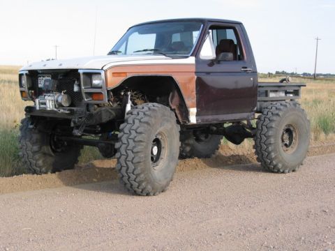 1981 Ford Bronco - This heavily modified pickup truck features oversized tires and a flatbed conversion, suggesting a custom build rather than a stock 1981 Fo…
