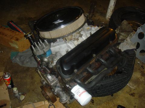 1986 Ford Mustang - Engine components, including an air cleaner and oil filter, are laid out on a workshop floor.